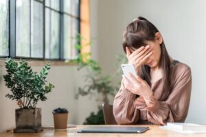 カフェでスマホを持って困っている女性